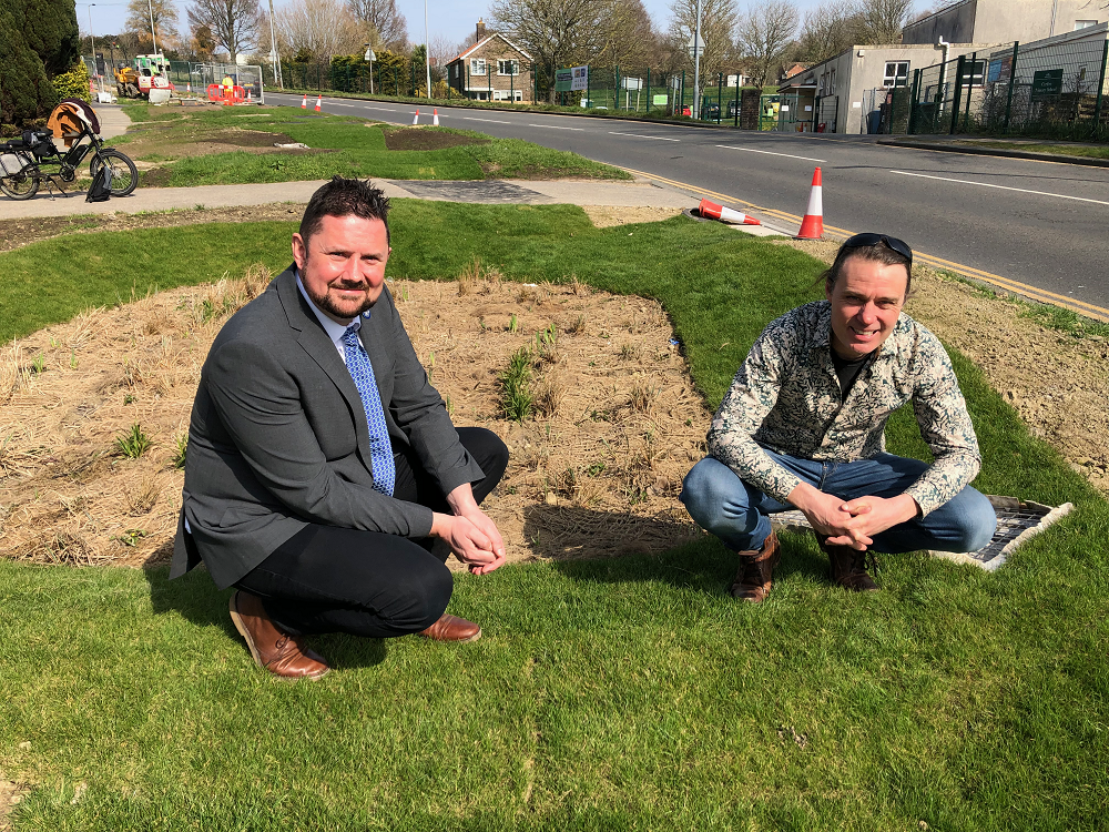 "a picture of two men squtting down on a grass verge"