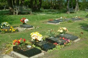 "lawn with memorial tablets lying on the ground with flowers beside them "