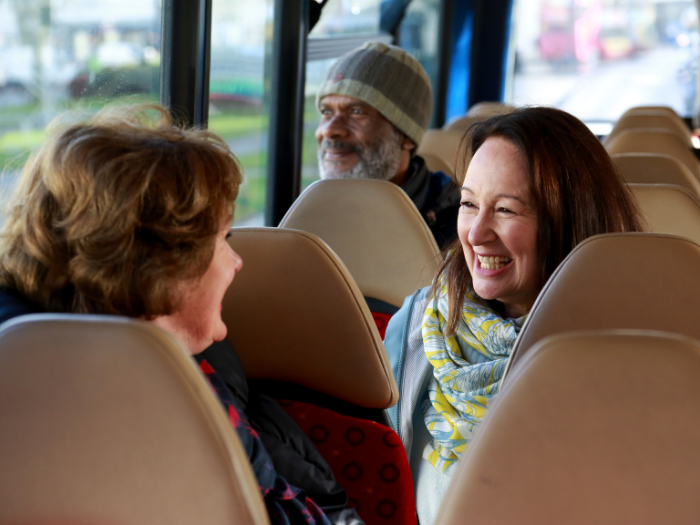 "three people sitting on a bus"