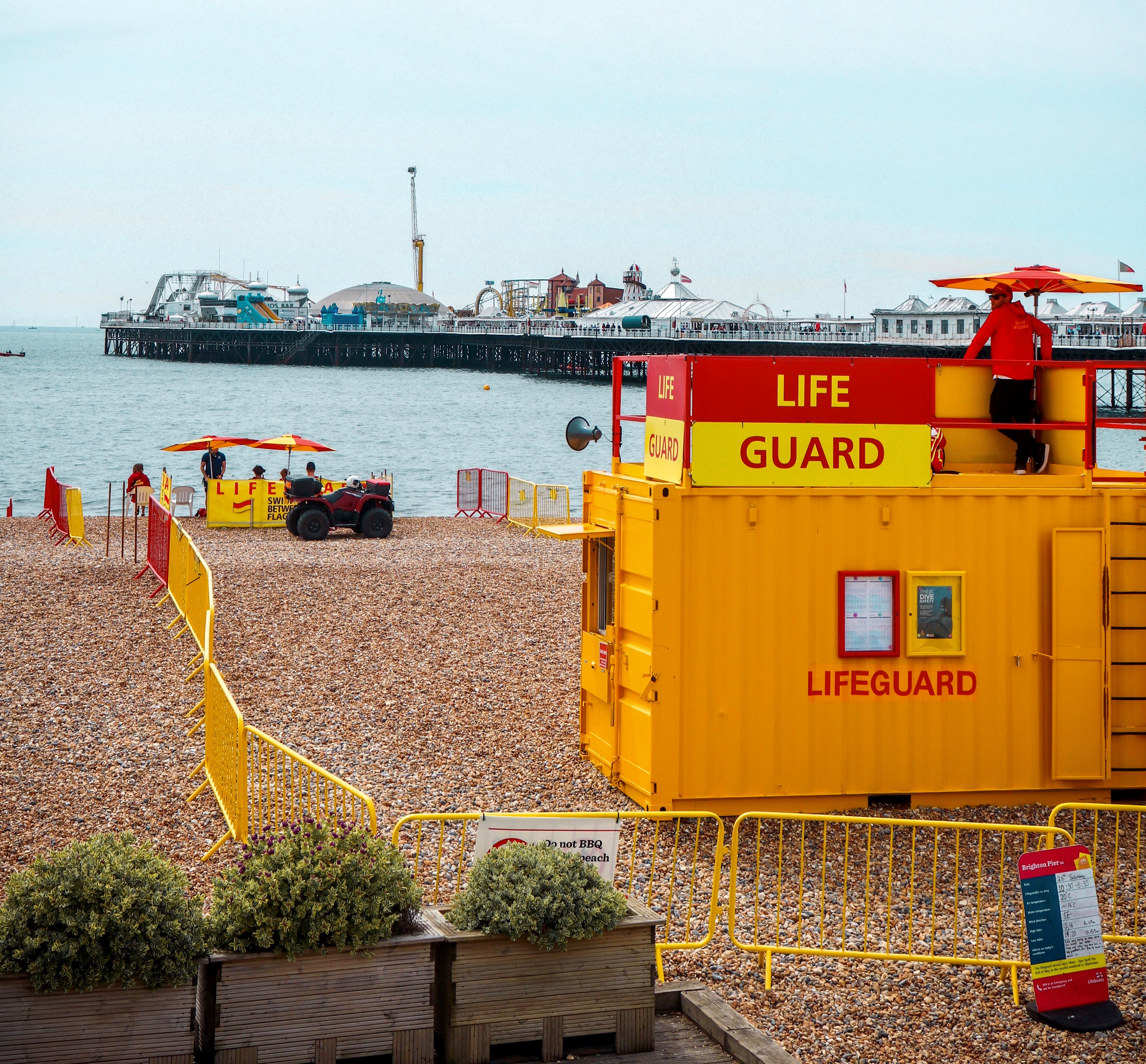 "Lifeguard post, a yellow shipping container with a red and yellow 'lifeguard' sign, surrounded by yellow and red railings."