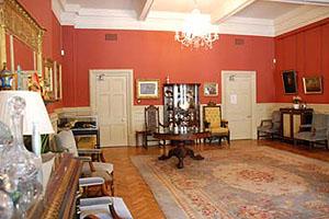 Photo of the Mayers Parlour with old fashioned furniture around the edge of the room and a dark red rug