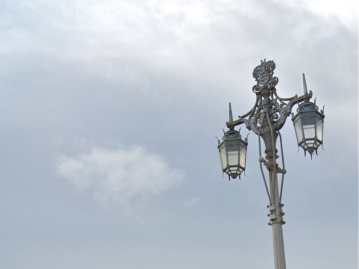 "A streetlight with two glass lanterns hanging from a patterned bracket"