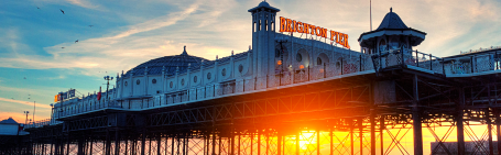 "Brighton Pier at sunset, the sun is shining through underneath the pier"