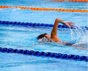 A swimmer does front crawl in a pool. They are between two blue lane ropes.