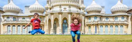 2 children smiling and jumping in front of the Royal Pavillion