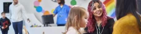 Health workers talking to adults and children in a reception area