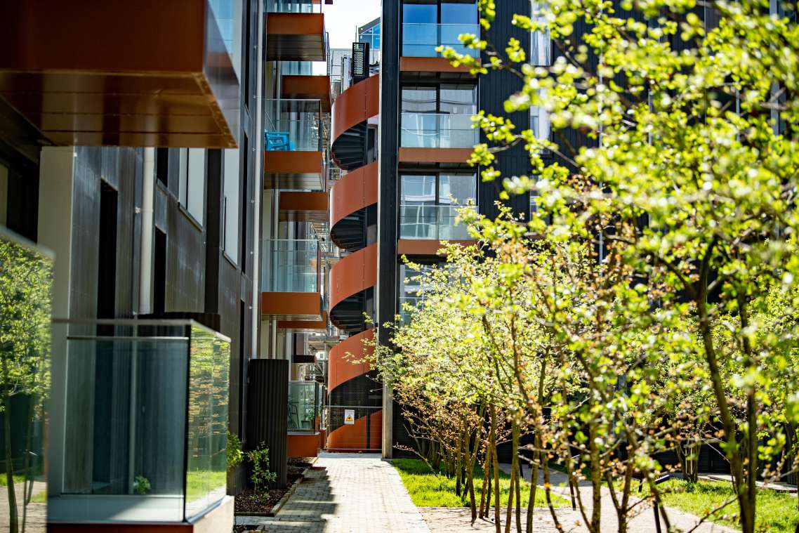 Trees in the foreground compliment the architecture of the housing block, with its glass balconies and rust-finished spiral staircase