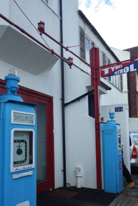 Two historical petrol pumps. They are chunky, free standing, blue metal boxes, about 6 feet high.