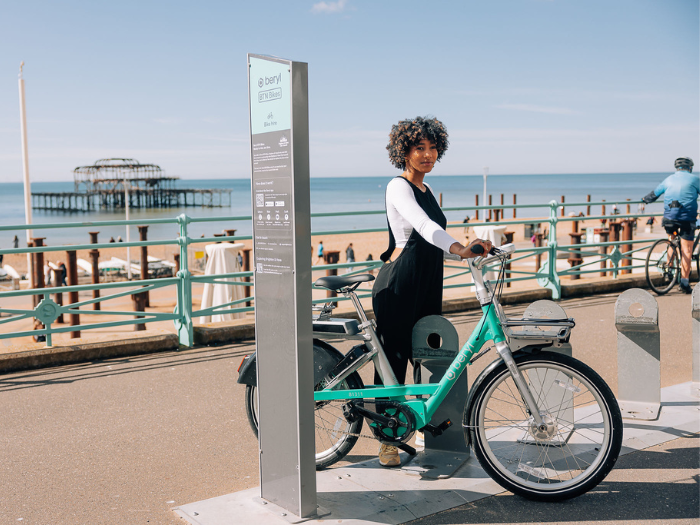 A person standing next to a bike on a seafront promenade