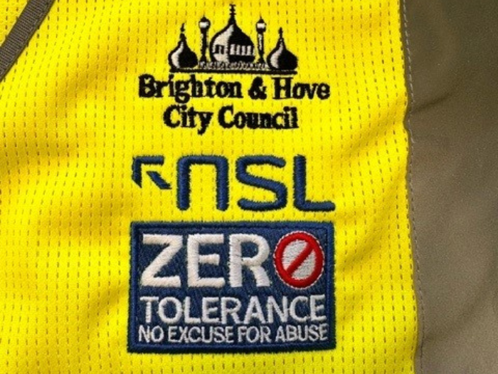 A hi viz vest with a council badge, another reading NSL and a third which reads Zero Tolerance, no excuse for abuse'