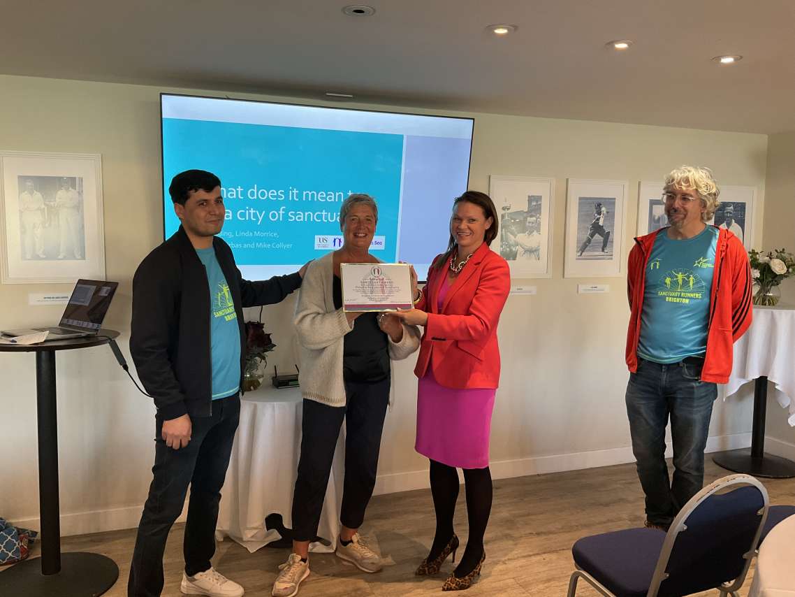 The image shows Libraries Manager Norah Carr receiving the Libraries of Sanctuary award with Council Leader Bella Sankey and Mike Collyer and Fatehullah Naserzai of Sanctuary on Sea.