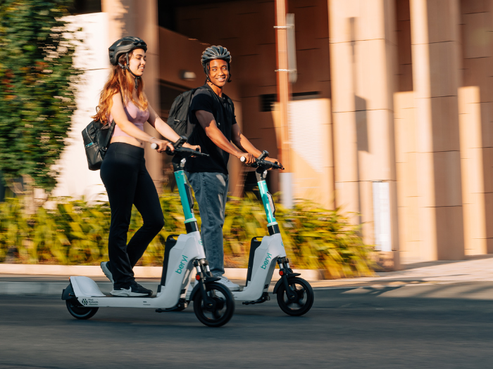 Two people riding e-scooters