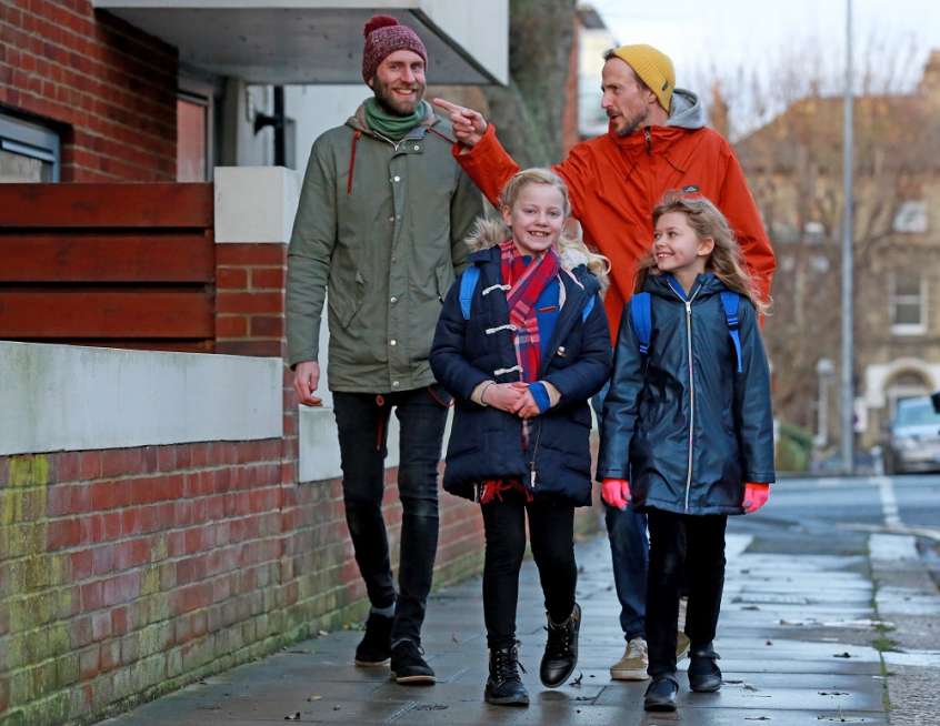 Two adults and two children walking.