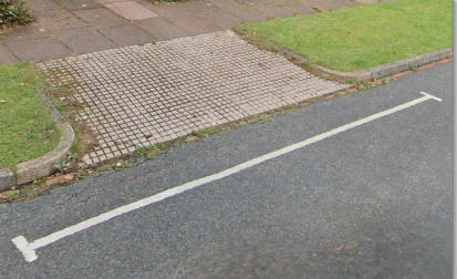 An example of white access protection marking next to a driveway