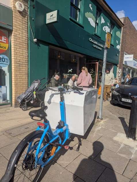 On a sunny day, an eCargo bike is parked outside Chasing Rabbits coffee house in Brighton