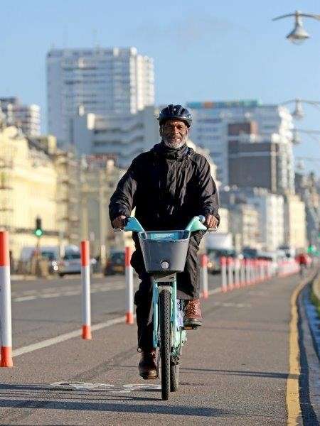 Man on a hired Brighton bike, cycling down the seafront cycle lane.