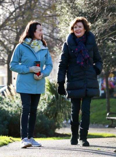 2 people walking through a park in Brighton. 