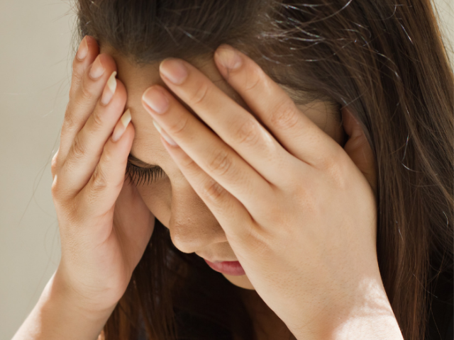 A photo of a teenage girl looking upset holding her head 