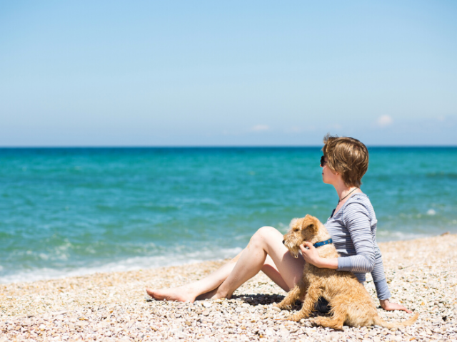 Women with dog sitting on sandy beach