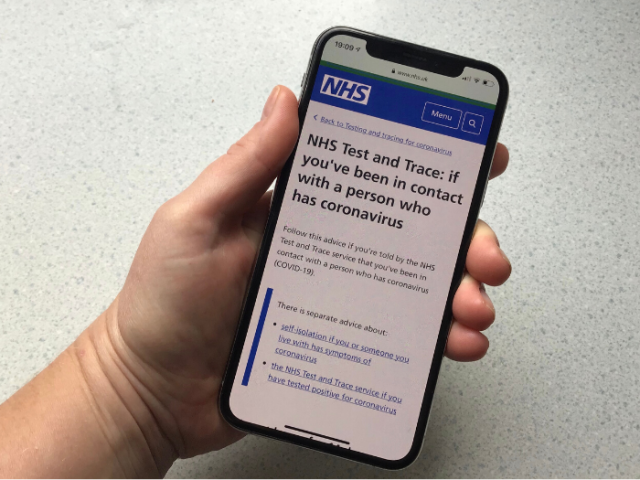 Hand holding a phone showing the Test and Trace information