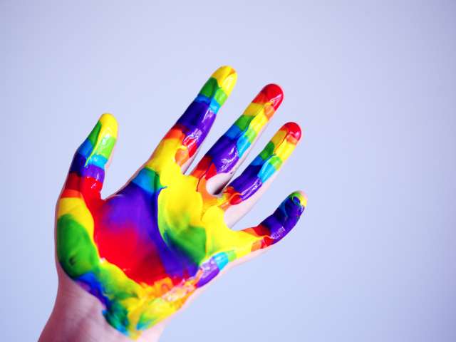 Hand splashed with colours red, green, yellow and blue