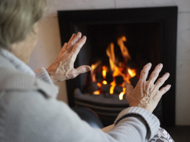 Woman warming her hands by a gas fire