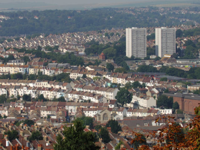 View of houses in Brighton, looking down on to streets and blocks of flats, with hills in the background.