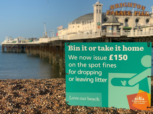 Littering sign on Brighton beach with pier in the background 