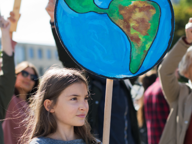 Photo of a young girl holding a sign illustrating the earth at a gathering