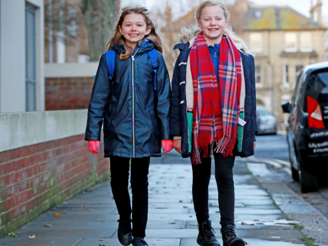 Two primary school children walking on a pavement