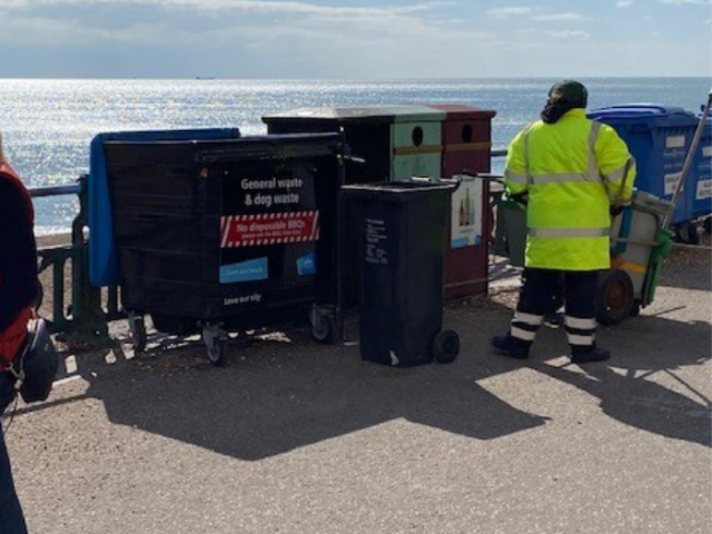 Image of street cleaner emptying bins on Hove promenade. 