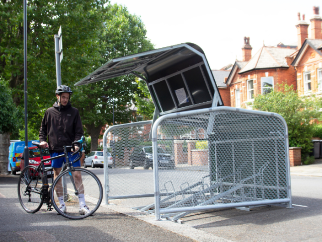 A picture of a man with a bike next to a small storage unit