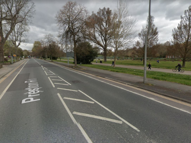 A picture of a road with a park in the background