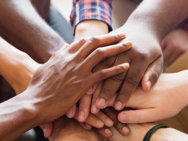A photo of a number of people's hands overlapping representing support