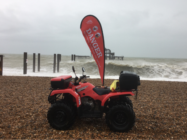 Picture of a seafront quad bike on the beach carrying a large danger sign