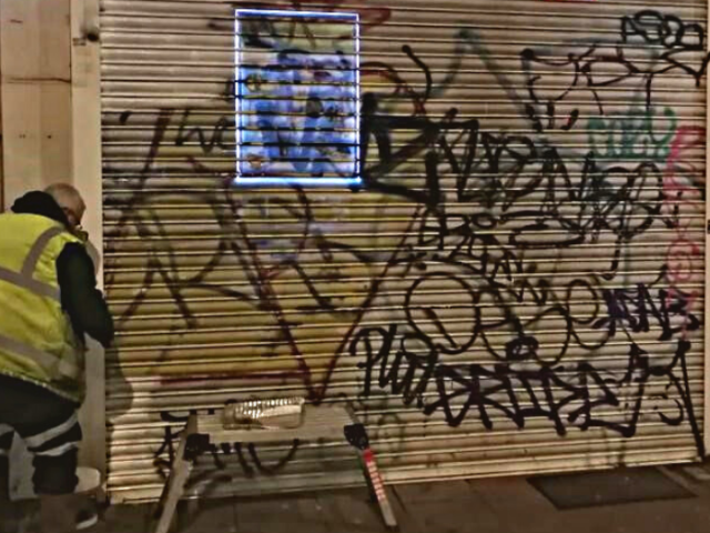 Member of the council's team removing graffiti from a shutter.