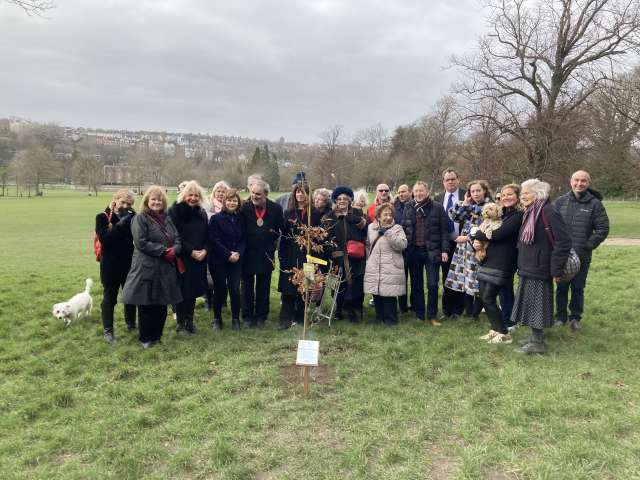 Group of people stood around the newly planted Oak tree in Preston Park