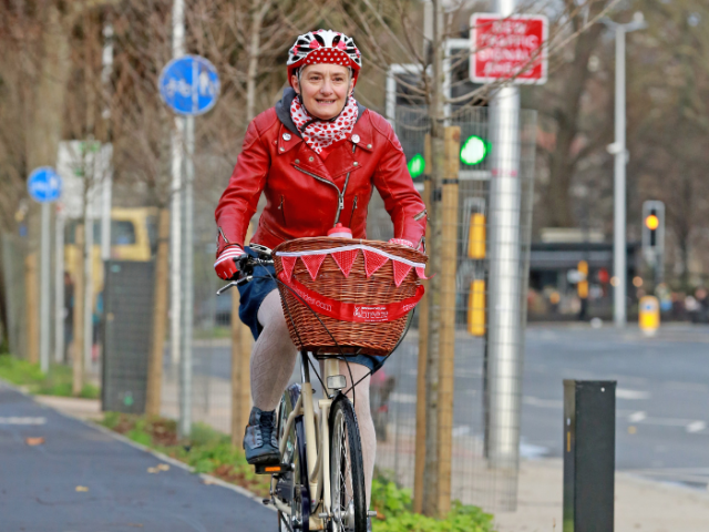 A picture of a woman on a bike with a basket on the front