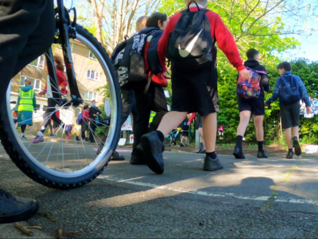 A picture of children walking and cycling near a school gate