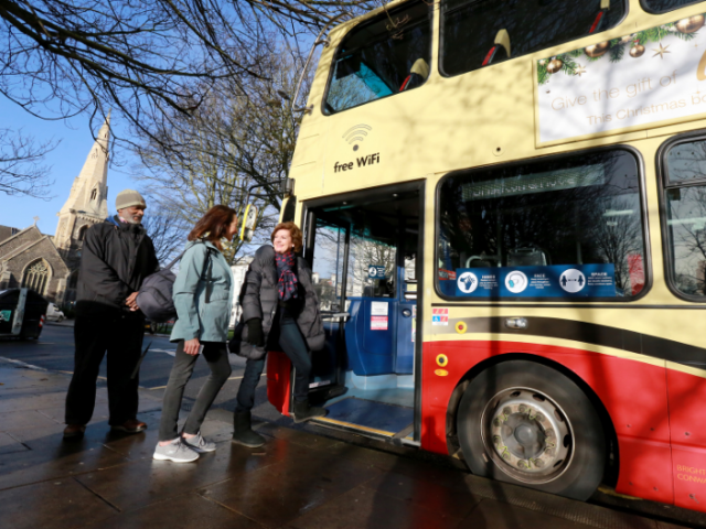 Three people queuing to get onto a bus