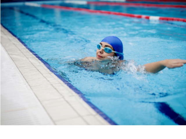 person in a swimming pool wearing a swim cap and goggles