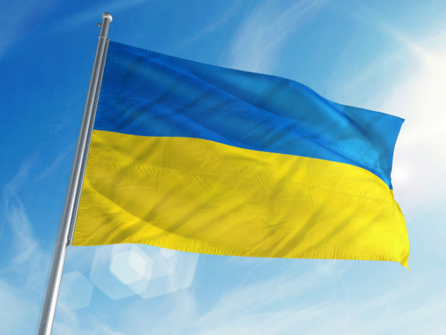 Photograph of the Ukrainian flag flying with blue sky in the background