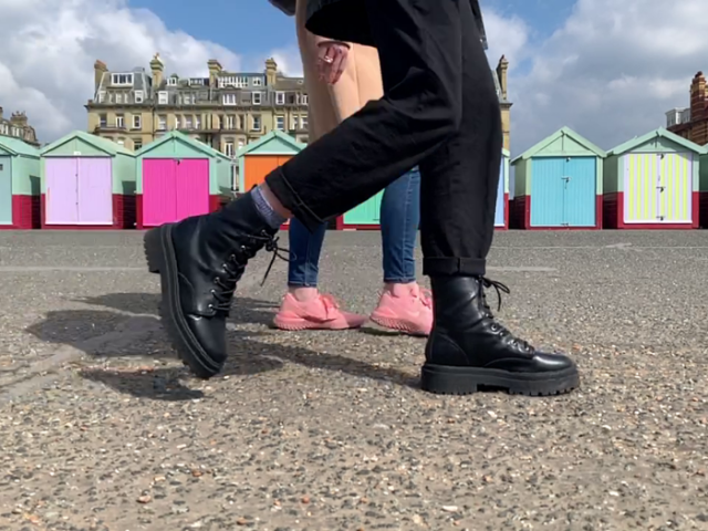 A picture of two people walking in front of some beach huts