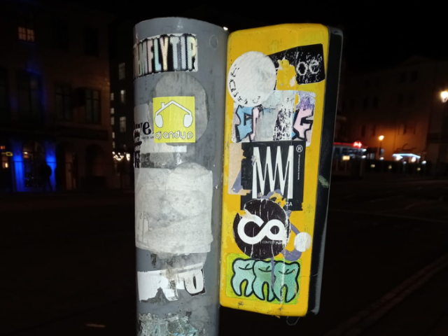 Photo of a road crossing control box defaced by fly-stickers