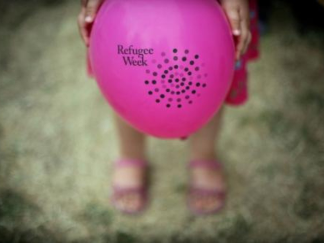 Photo of a child holding a pink Refugee Week branded balloon - photo credit Tobias Madden