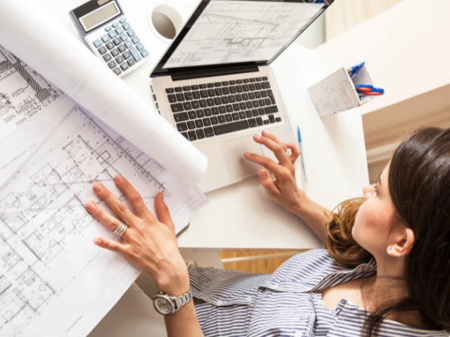 woman with laptop looking at architects drawings