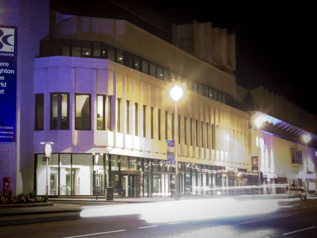 The Brighton Centre exterior taken at night, lit up purple and white