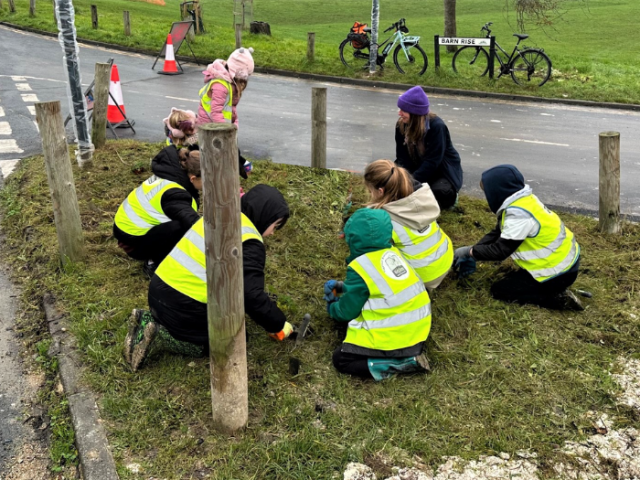 children and adults planting on some grass