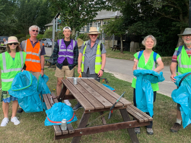 Photograph of a group of happy looking volunteers wearing hi vis vests and carrying litter picking tools and bags.