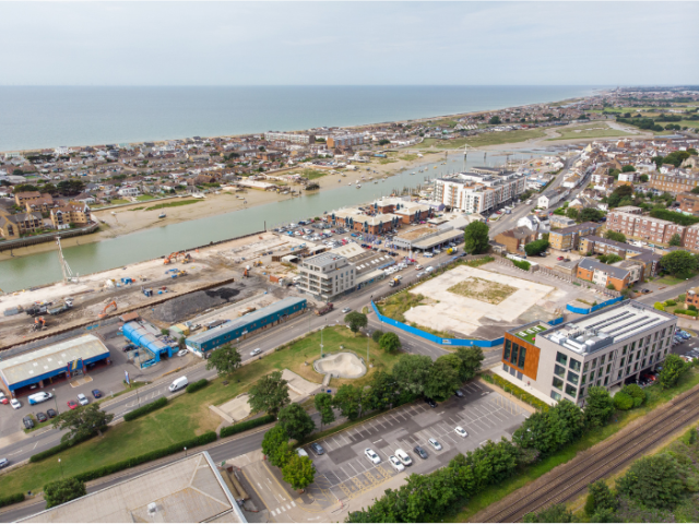 An aerial image of part of Shoreham Harbour showing the east - west rail line, A27 road, the inner harbour adn the sea beyond.